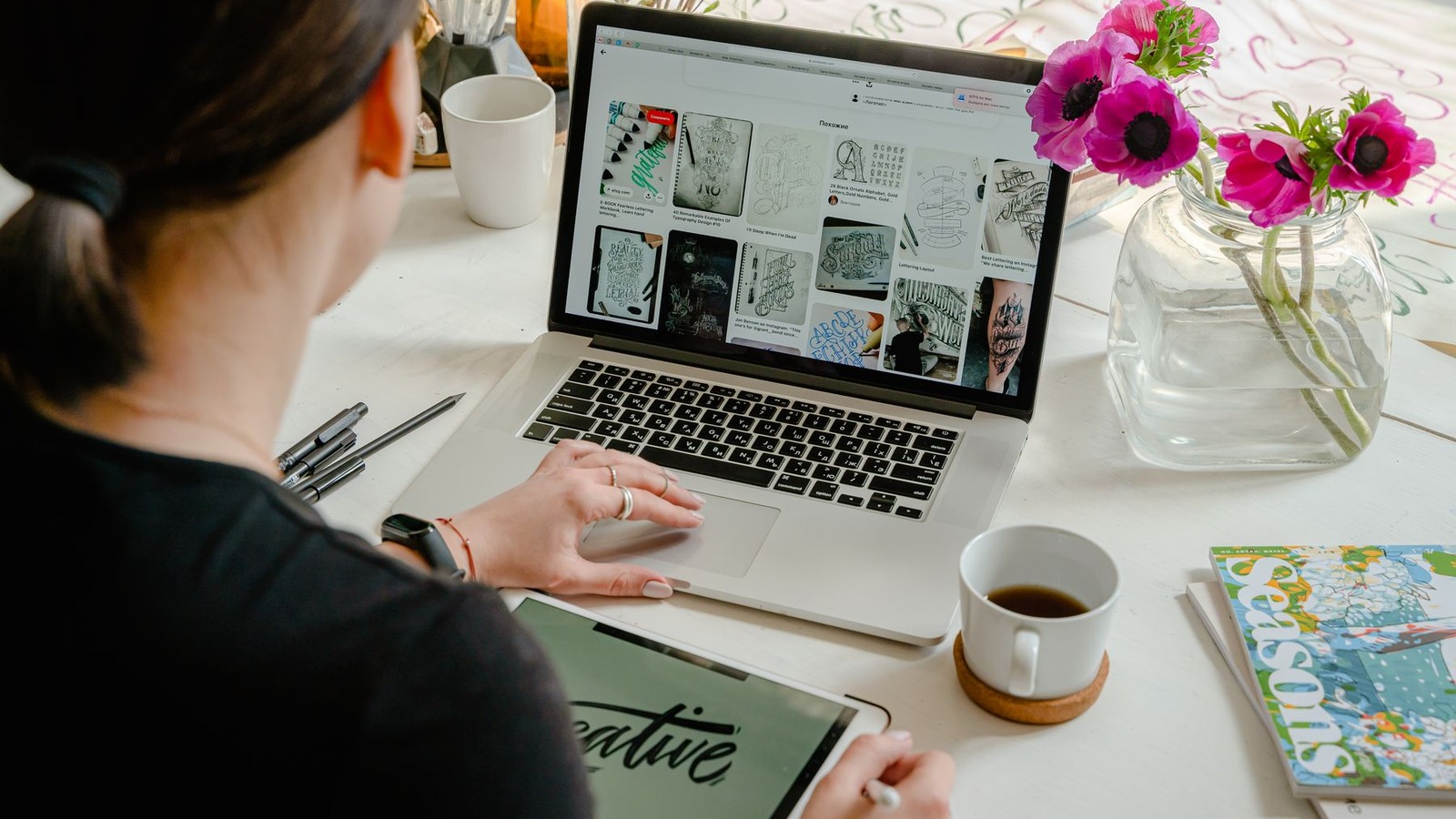 A creative professional using a laptop and tablet at a bright desk